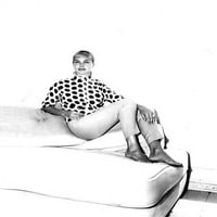 Joan drvo iz 1960-ih smiješi se, odmara se na kauču s golim nogama na fotografiji