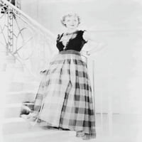 Bette Davis pozirala je na stepenicama s rukom na struku, noseći crni prozirni gornji dio bez rukava i dugu prugastu